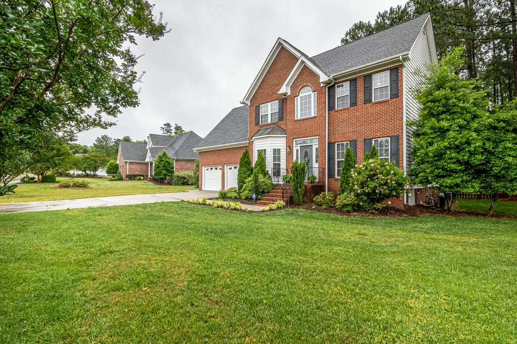 Brick two-story home with a full green front lawn