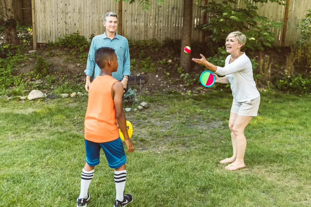 Family playing catch on a sunny backyard lawn